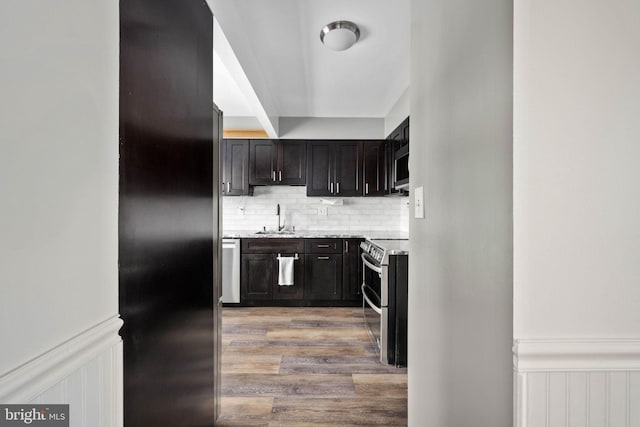 kitchen featuring sink, backsplash, dark brown cabinets, stainless steel appliances, and light stone counters