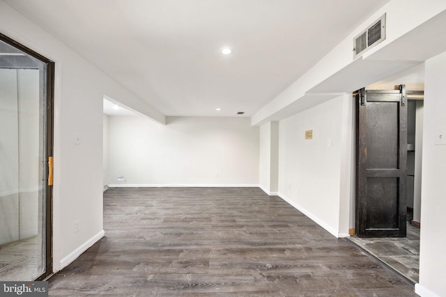 basement with a barn door and dark hardwood / wood-style floors