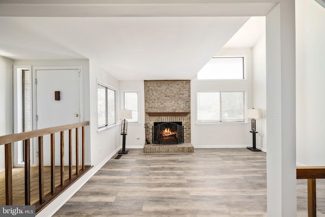 unfurnished living room featuring a fireplace, vaulted ceiling, and light wood-type flooring