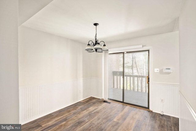 unfurnished dining area with dark hardwood / wood-style floors and a chandelier