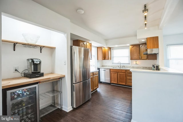 kitchen with sink, wooden counters, appliances with stainless steel finishes, dark hardwood / wood-style floors, and beverage cooler