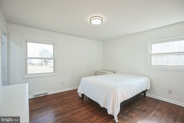 bedroom featuring multiple windows and dark wood-type flooring