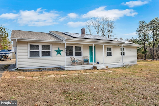 ranch-style home with a porch, a front lawn, and solar panels