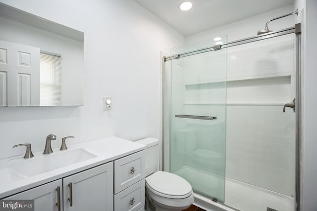 bathroom featuring vanity, a shower with shower door, and toilet