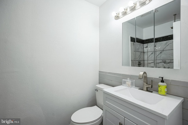 bathroom featuring vanity, tile walls, and toilet