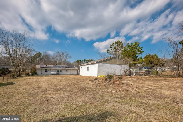 back of property featuring a yard and solar panels