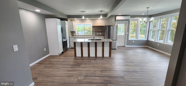 kitchen with stainless steel refrigerator, hanging light fixtures, sink, a center island with sink, and dark hardwood / wood-style floors