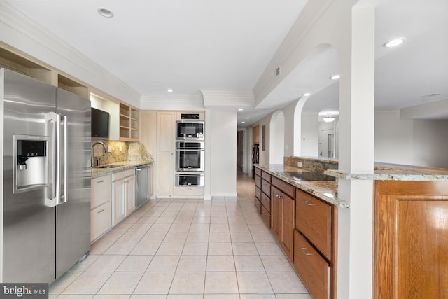 kitchen with light stone countertops, appliances with stainless steel finishes, tasteful backsplash, sink, and light tile patterned flooring