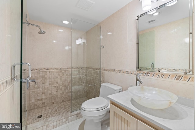 bathroom featuring tile patterned flooring, tile walls, toilet, a shower with shower door, and vanity