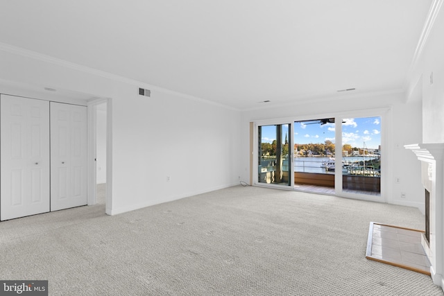 unfurnished living room with light carpet, a tile fireplace, ornamental molding, and a water view