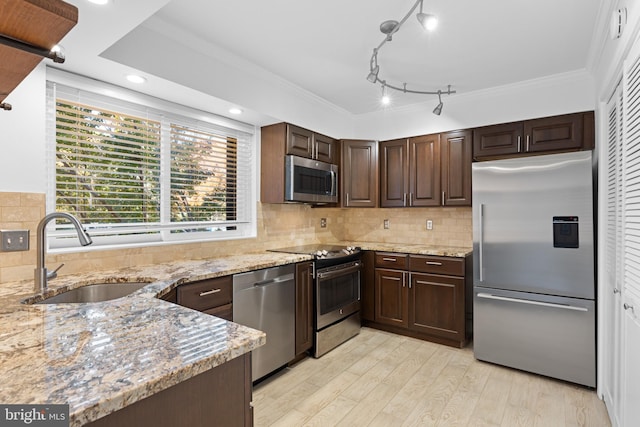 kitchen with sink, stainless steel appliances, light stone countertops, decorative backsplash, and dark brown cabinetry