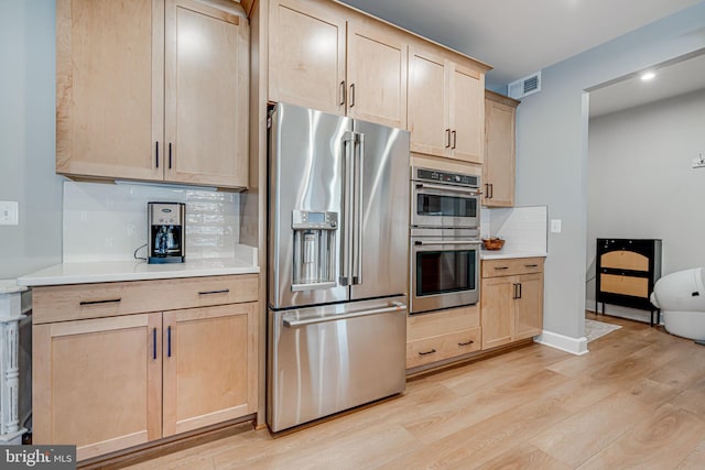 kitchen with stainless steel appliances, light countertops, light brown cabinets, and visible vents