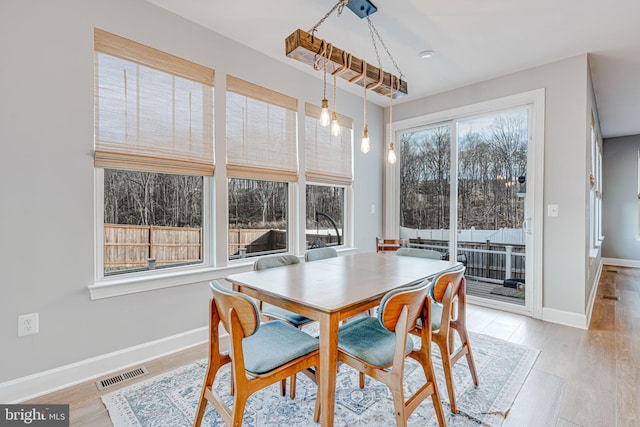 dining area with baseboards, visible vents, and light wood finished floors