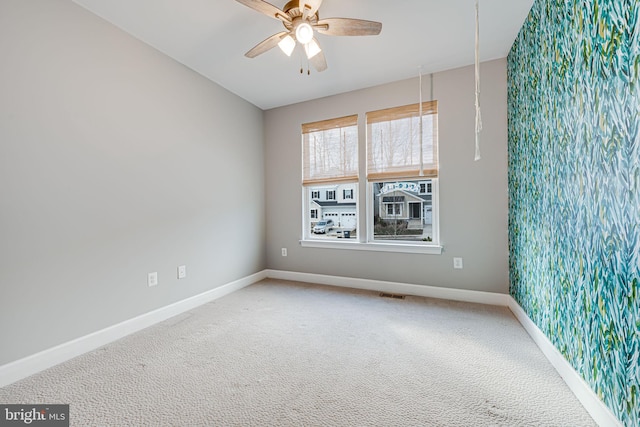 unfurnished room featuring carpet floors, a ceiling fan, visible vents, and baseboards