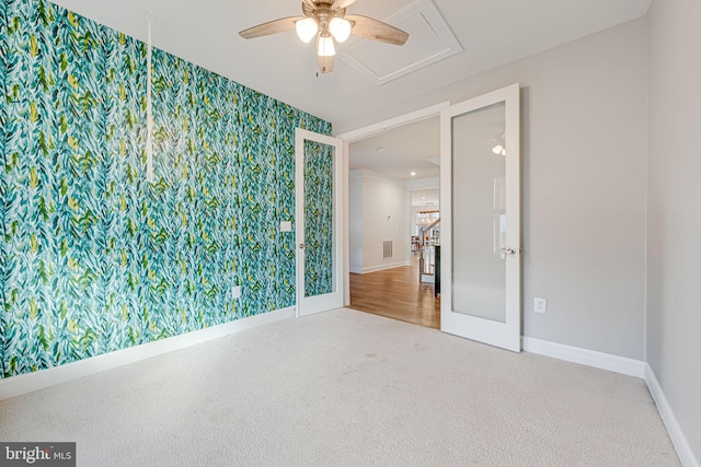 carpeted empty room with wallpapered walls, a ceiling fan, and baseboards