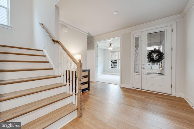 entryway featuring stairs, ornamental molding, light wood-type flooring, and baseboards