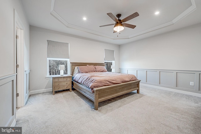 bedroom featuring light carpet, wainscoting, a tray ceiling, a decorative wall, and recessed lighting