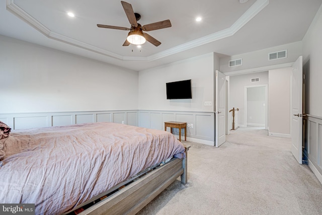 bedroom with light carpet, a tray ceiling, visible vents, and crown molding