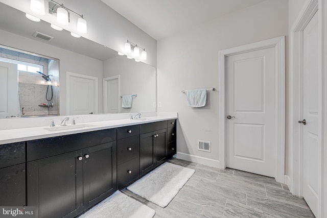 bathroom with visible vents, a sink, tiled shower, and double vanity