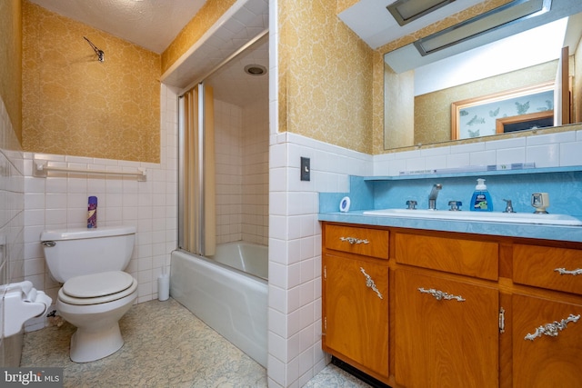 full bathroom with toilet, vanity, enclosed tub / shower combo, and tile walls