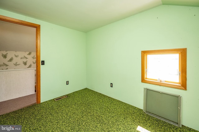 spare room featuring radiator heating unit, carpet flooring, and lofted ceiling