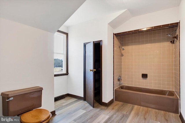 bathroom featuring tiled shower / bath, wood-type flooring, and toilet