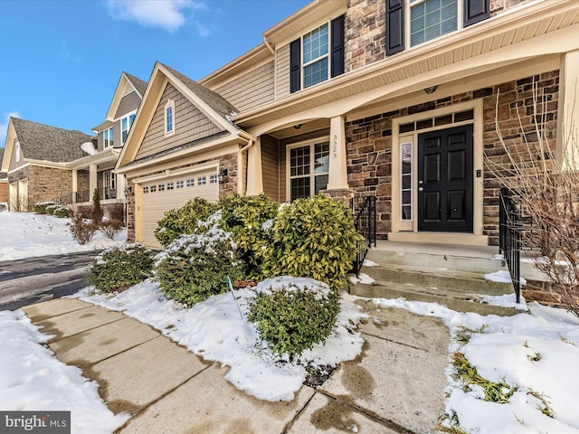 snow covered property entrance featuring a garage