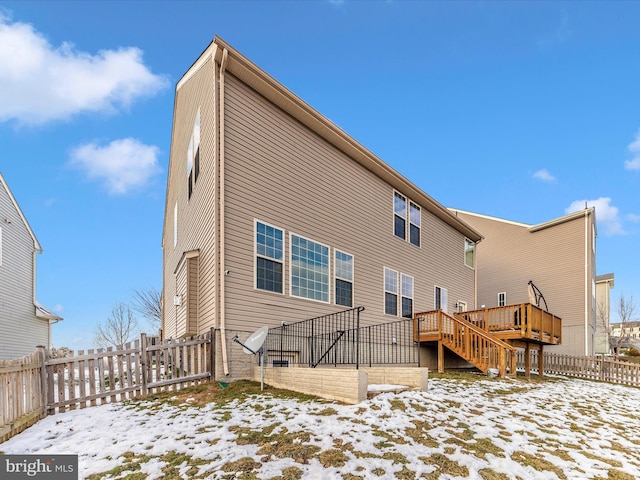 snow covered back of property featuring a deck