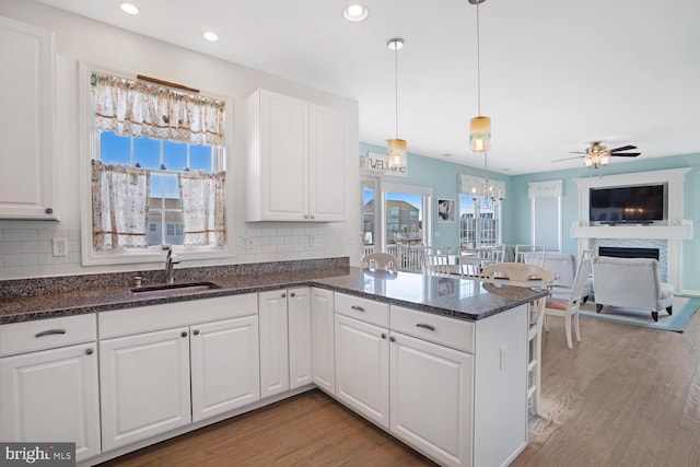 kitchen with tasteful backsplash, white cabinetry, sink, and pendant lighting