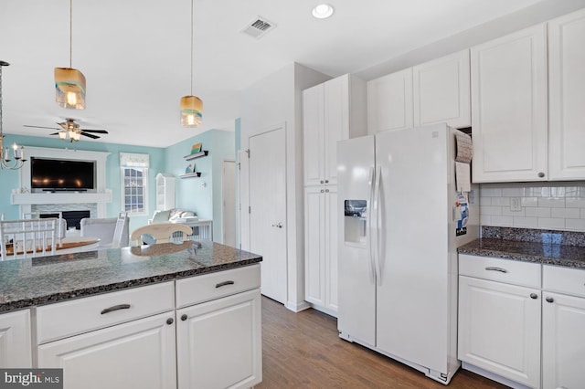 kitchen featuring dark hardwood / wood-style flooring, white fridge with ice dispenser, pendant lighting, decorative backsplash, and white cabinets