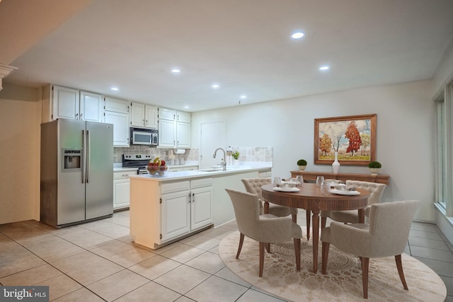 kitchen with white cabinetry, light tile patterned floors, stainless steel appliances, and tasteful backsplash