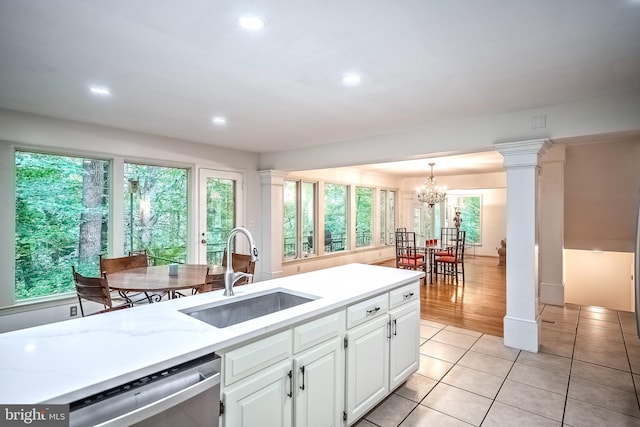 kitchen featuring dishwasher, hanging light fixtures, ornate columns, sink, and white cabinetry