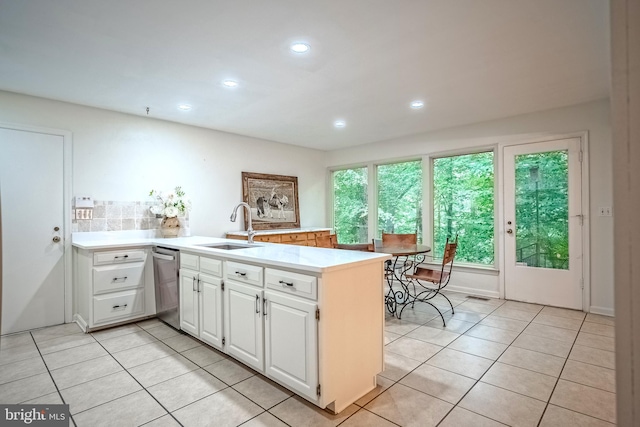 kitchen featuring light tile patterned floors, stainless steel dishwasher, white cabinets, sink, and kitchen peninsula