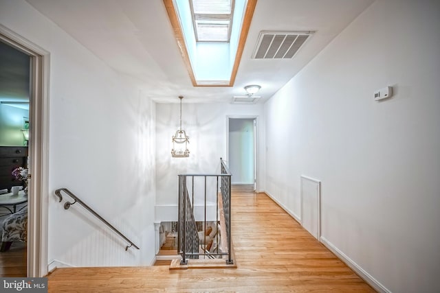 hall with hardwood / wood-style floors and a skylight