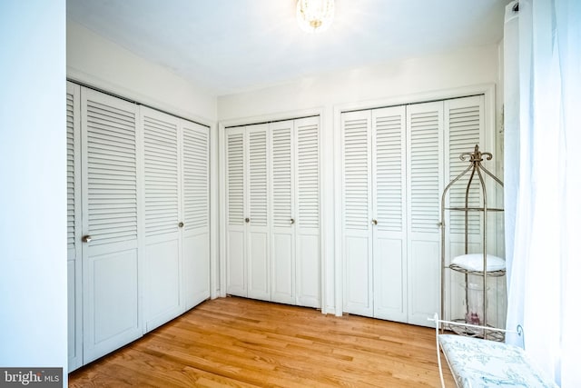 unfurnished bedroom with multiple closets and light hardwood / wood-style flooring