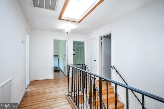 hall featuring a skylight and light wood-type flooring