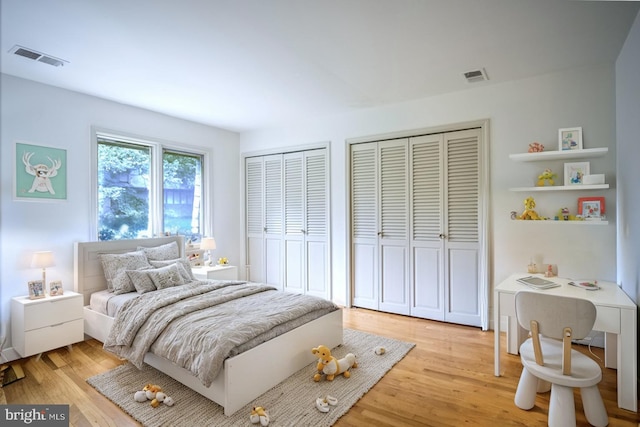 bedroom with multiple closets and light hardwood / wood-style flooring