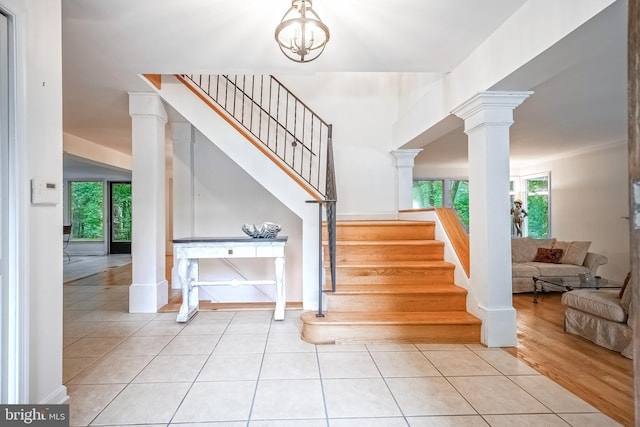 stairway featuring a wealth of natural light, ornate columns, and tile patterned flooring