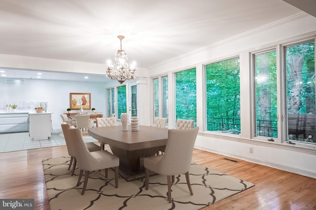 dining space featuring a notable chandelier, light hardwood / wood-style flooring, and crown molding