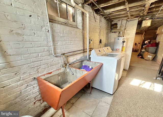 clothes washing area with washing machine and clothes dryer, brick wall, and sink