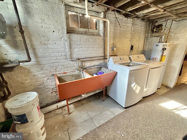 laundry area featuring water heater, brick wall, sink, and washing machine and clothes dryer