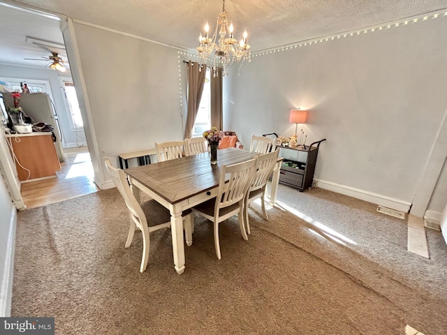 dining space featuring carpet flooring, ceiling fan with notable chandelier, and a textured ceiling