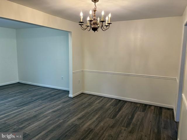 unfurnished room with dark hardwood / wood-style floors and a chandelier