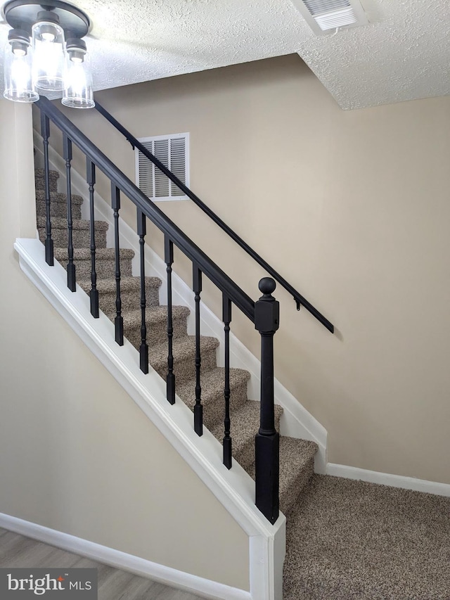 staircase featuring a textured ceiling