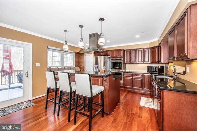 kitchen with crown molding, appliances with stainless steel finishes, island range hood, a kitchen island, and decorative light fixtures