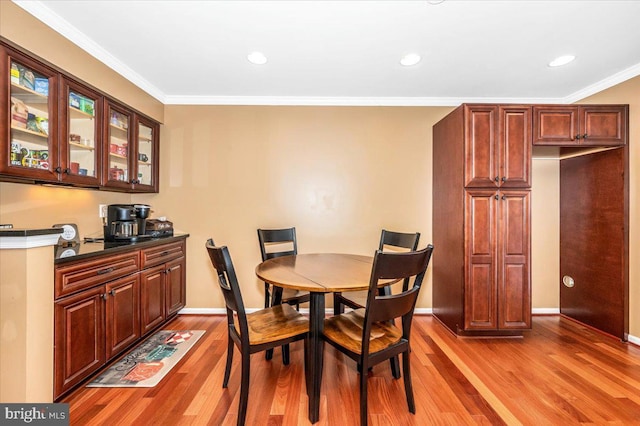 dining space with ornamental molding and light wood-type flooring