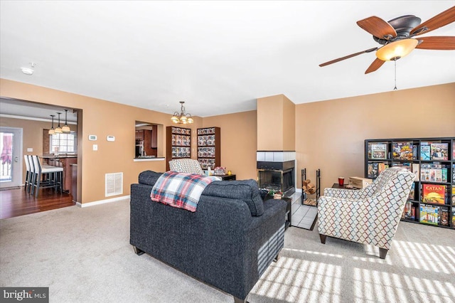 carpeted living room featuring ceiling fan with notable chandelier