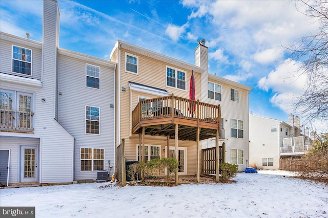 snow covered back of property featuring a wooden deck