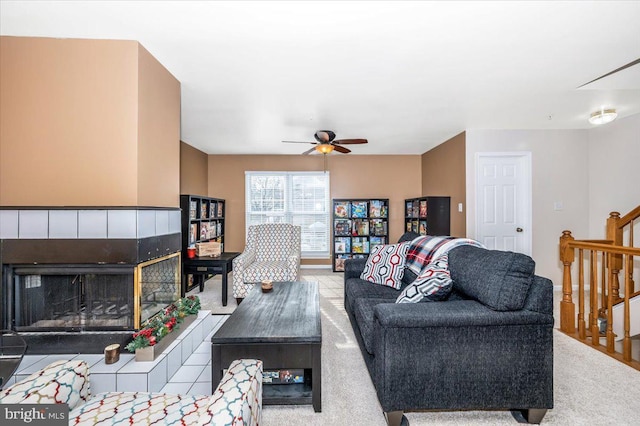 living room with a tile fireplace and ceiling fan