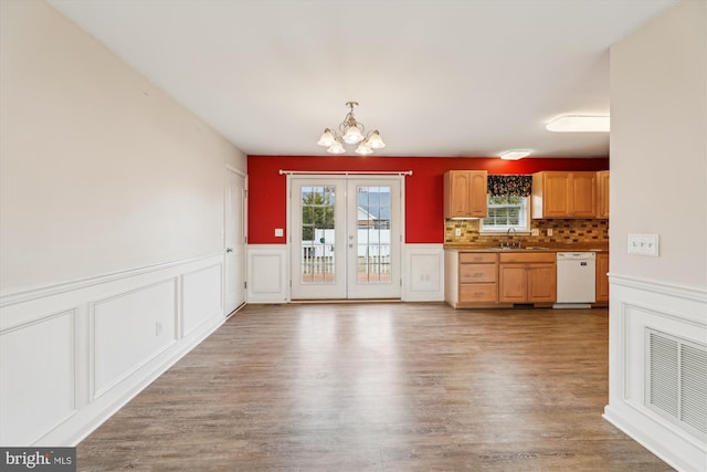 kitchen featuring sink, backsplash, white dishwasher, a notable chandelier, and light hardwood / wood-style floors